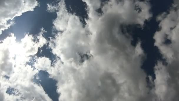 El lapso de tiempo de las nubes pasa rápidamente sobre la cámara en 4k. La cámara está dirigida verticalmente al cielo. Los rayos del sol hacen su camino a través de las nubes — Vídeo de stock