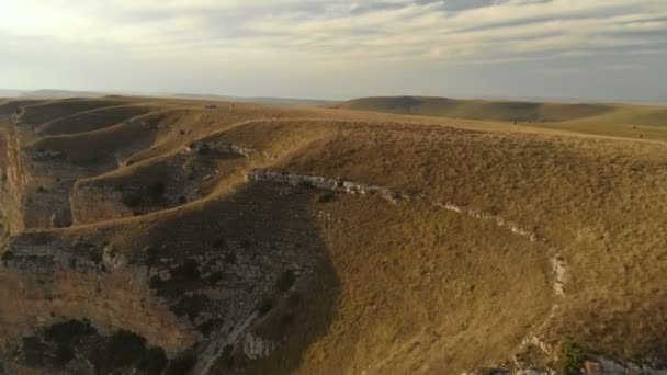 Antenne: Vlucht over een hoge rots rots, onthullen een weergave van de pass in Rusland in de noordelijke Kaukasus. Luchtfoto's van de weg in de ondergaande zon. Vlucht naast de rots — Stockvideo