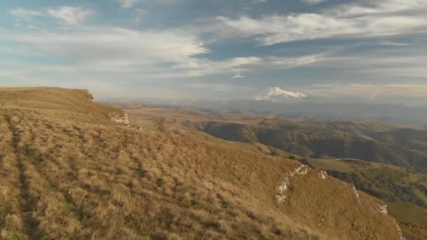 Κεραία: Πτήση πάνω από ένα ψηλό βράχο βράχο, αποκαλύπτοντας μια θέα από το πέρασμα στη Ρωσία στον Βόρειο Καύκασο. Αεροφωτογραφία του δρόμου στη δύση του ήλιου. Πτήση δίπλα στο βράχο — Αρχείο Βίντεο