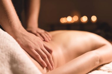 Yakın çekim erkek eller şifa yaparken bir koyu kozmetik ofiste genç bir kız için yağı ile masaj. Karanlık anahtar