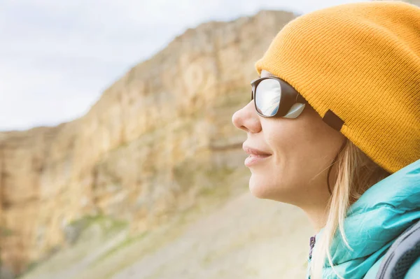 Retrato de cerca de una chica viajera con sombrero y gafas de sol trepadoras. Chica feliz en el fondo de las rocas — Foto de Stock