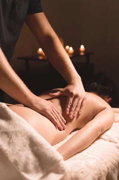 Close-up mannelijke handen doen helende massage met olie aan een jong meisje in een donkere cosmetologie kantoor. Donkere sleutel — Stockfoto