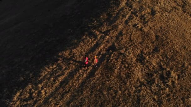 Vue aérienne d'un voyageur de deux filles avec des sacs à dos et des caméras se promener à travers les collines entre les rochers épiques dans les montagnes. Les filles photographes avec leurs appareils photo au coucher du soleil 