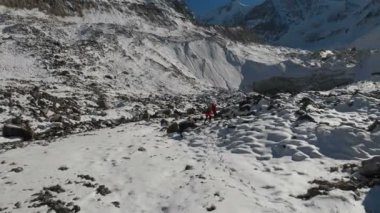 İki kız seyahat sırt çantaları ve kameralar ile havadan görünümü kar üzerinden gidin ve taş'a buzul dağlarda epik kayaların arasında. Kızlar fotoğrafçılar fotoğraf makinelerine batımında ile