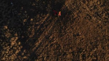 İki kız seyahat sırt çantaları ve kameralar ile havadan görünümü üzerinden tepeler dağlarda epik kayalar arasında yürüyün. Kızlar fotoğrafçılar fotoğraf makinelerine batımında ile