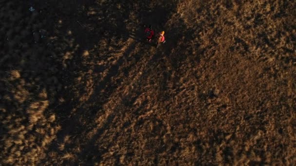 Flygfoto över två flickor resenär med ryggsäckar och kameror promenera genom kullarna mellan episka stenarna i bergen. Flickor fotografer med sina kameror vid solnedgången — Stockvideo