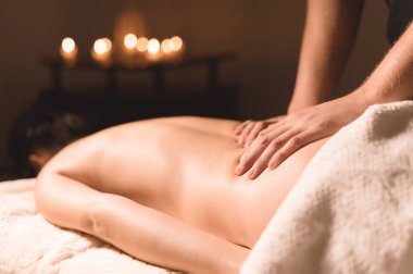 Yakın çekim erkek eller şifa yaparken bir koyu kozmetik ofiste genç bir kız için yağı ile masaj. Karanlık anahtar