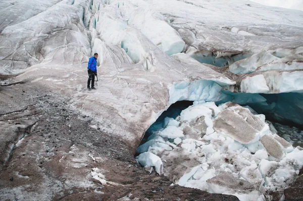 戴着帽子和太阳镜的旅行者坐在冰川上的雪山上。自然环境中的旅行者 — 图库照片