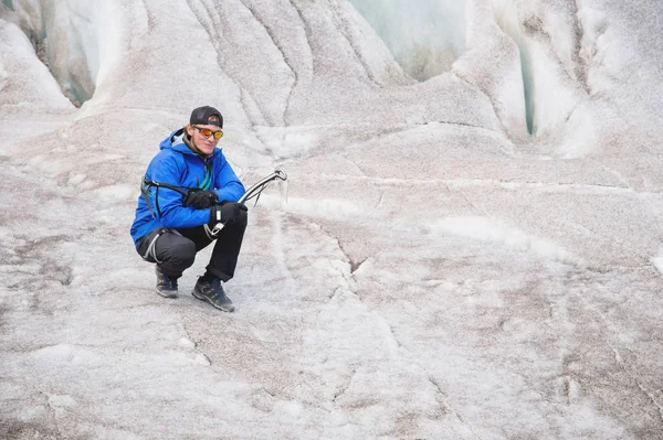 Le voyageur en casquette et lunettes de soleil est assis dans les montagnes enneigées sur le glacier. Voyageur dans un environnement naturel — Photo