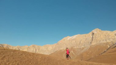 İki kız seyahat sırt çantaları ve kameralar ile havadan görünümü üzerinden tepeler dağlarda epik kayalar arasında yürüyün. Kızlar fotoğrafçılar fotoğraf makinelerine batımında ile