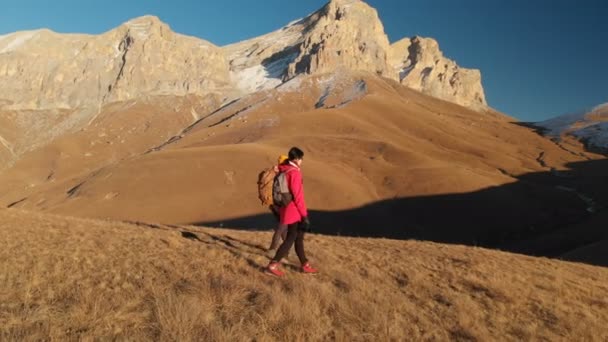 İki kız seyahat sırt çantaları ve kameralar ile havadan görünümü üzerinden tepeler dağlarda epik kayalar arasında yürüyün. Kızlar fotoğrafçılar fotoğraf makinelerine batımında ile — Stok video