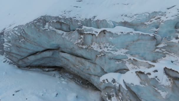 Vista aérea close-up borda de uma geleira fluindo coberto com neve e pedras altas nas montanhas. Destruição natural dos glaciares de fusão e aquecimento global — Vídeo de Stock