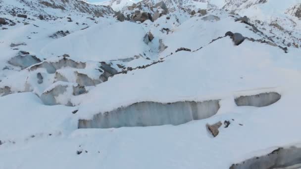 Vista aérea close-up borda de uma geleira fluindo coberto com neve e pedras altas nas montanhas. Destruição natural dos glaciares de fusão e aquecimento global — Vídeo de Stock