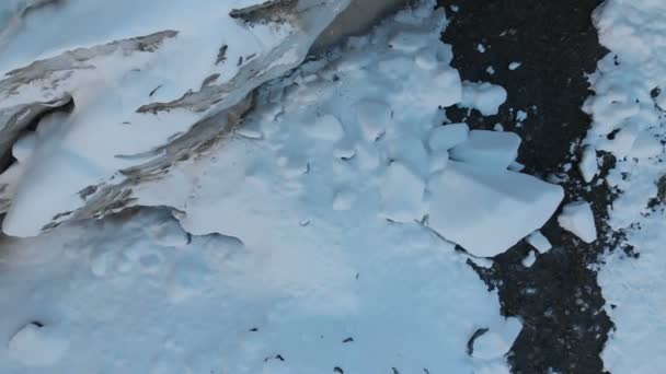 Luchtfoto van de geboorte van een rivier berg in een gletsjer. De rivier stroomt uit de ijsgrot. Berg rivier van de weergave van de winter in de bergen — Stockvideo