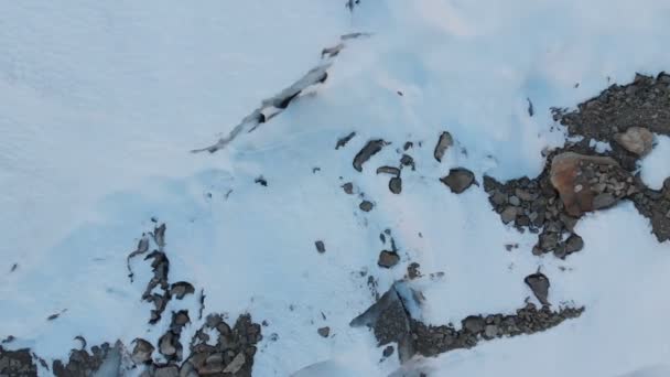 Vista aérea primer plano de un glaciar que fluye cubierto de nieve y piedras en lo alto de las montañas. Destrucción natural de glaciares derretidos y calentamiento global — Vídeo de stock