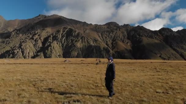 Vista aérea de uma fotógrafa caminhando em um planalto nas montanhas com sua câmera no fundo de rochas e montanhas. Passatempos prediletos na natureza 4k — Vídeo de Stock