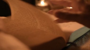 Bir büyük yakın çekim kız sihirbaz bir büyü bir kitap arıyorum mum ışığı ile karanlık bir odada. Düşük anahtar canlı kamera. Mistik. Küçük Dof