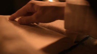 Bir büyük yakın çekim kız sihirbaz bir büyü bir kitap arıyorum mum ışığı ile karanlık bir odada. Düşük anahtar canlı kamera. Mistik. Küçük Dof