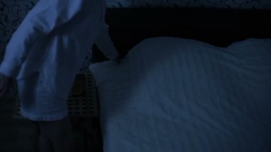 Orta çekim kız gece pijama yatağa gelip yatağa gidiyor. Uyku için hazırlık. Amerikan gece etkisi. Düşük anahtar soğuk ışık İmitasyon gece