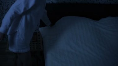 Orta çekim kız gece pijama yatağa gelip yatağa gidiyor. Uyku için hazırlık. Amerikan gece etkisi. Düşük anahtar soğuk ışık İmitasyon gece