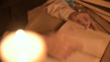 Bir büyük yakın çekim kız sihirbaz bir büyü bir kitap arıyorum mum ışığı ile karanlık bir odada. Düşük anahtar canlı kamera. Mistik. Küçük Dof.