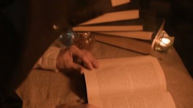 Bir büyük yakın çekim kız sihirbaz bir büyü bir kitap arıyorum mum ışığı ile karanlık bir odada. Düşük anahtar canlı kamera. Mistik. Küçük Dof