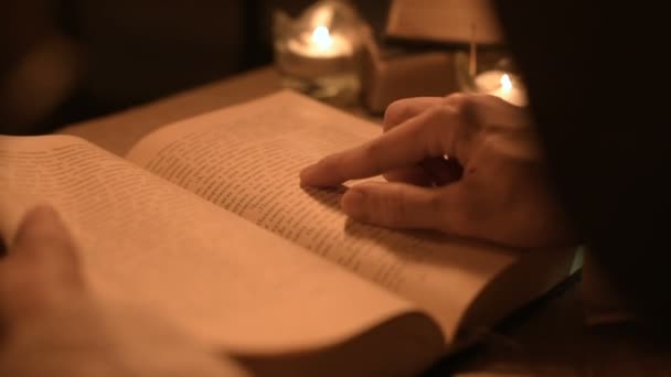 Большая девочка-фокусница крупным планом в темной комнате со свечами, ищущая заклинание в книге. Низкокачественная камера. Мистик. Небольшой DOF — стоковое видео