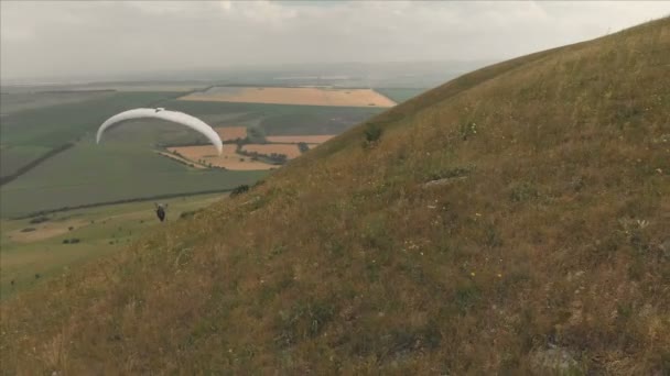 Luchtfoto van een professionele paraglider landt op een heuvel. Paraglider sport — Stockvideo