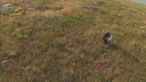 Luftaufnahme eines professionellen Gleitschirmfliegers, der nach der Landung mit dem Gleitschirm auf den Schultern die Seite eines Hügels hinuntergeht, um zum Startplatz zu gelangen. Gleitschirmsport — Stockvideo