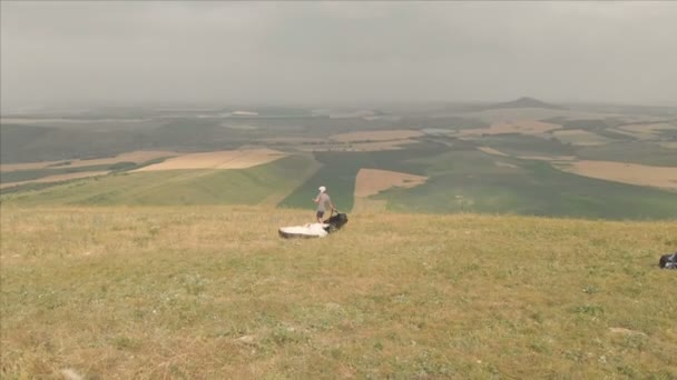 Letecký pohled na profesionální kluzák po přistání, sundá zařízení a helmu a jde na kopci. Kluzák sport — Stock video