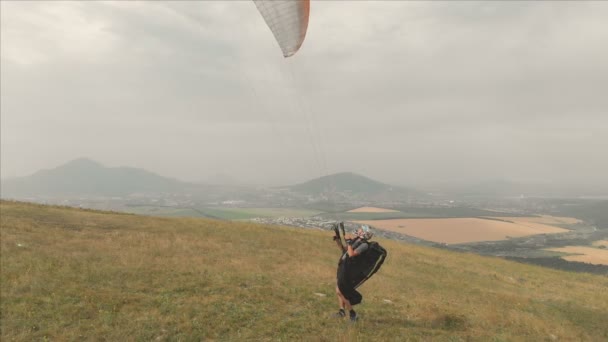 Flygfoto över en professionell paraglider tar ut från sidan av en kulle. Paraglider sport — Stockvideo