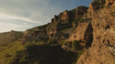 Günbatımı gökyüzü bulutlu bir kayalık vadide içinde düşük bir anahtar. Gün batımında rock massif dibinde arazi Panoraması. 4 k ılık ışık