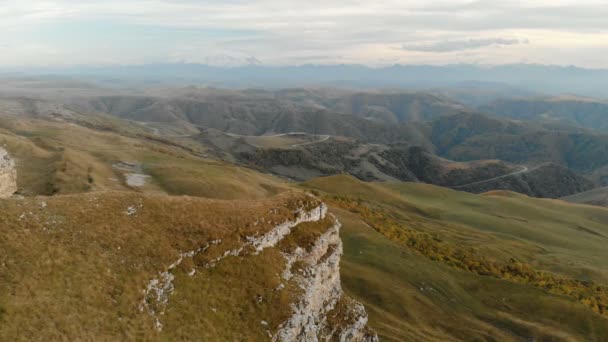 Antenn: Flygning över en hög klippa klippa, avslöjar en syn på passet i Ryssland i norra Kaukasus. Flygfotografering av vägen i den nedgående solen. Flyg bredvid berget — Stockvideo