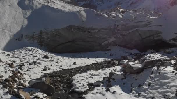 Veduta aerea della nascita di un fiume di montagna in un ghiacciaio. Il fiume scorre fuori dalla grotta di ghiaccio. Vista invernale fiume di montagna in montagna — Video Stock