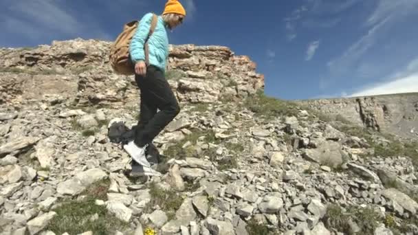 Ein Mädchen mit Rucksack geht in der Natur auf einem Plateau in der Nähe eines hohen Abgrunds spazieren. Reisekonzept — Stockvideo