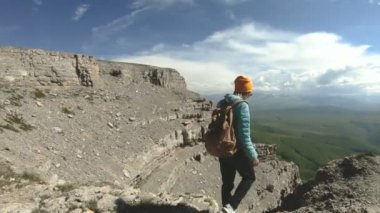 Bir kız bir sırt çantası ile doğada yüksek bir uçurumun yakınındaki bir plato üzerinde yürür. Seyahat kavramı