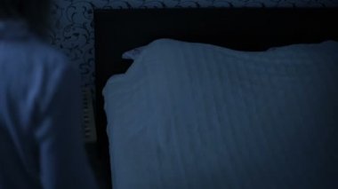 Orta çekim kız gece pijama yatağa gelip yatağa gidiyor. Uyku için hazırlık. Amerikan gece etkisi. Düşük anahtar soğuk ışık İmitasyon gece