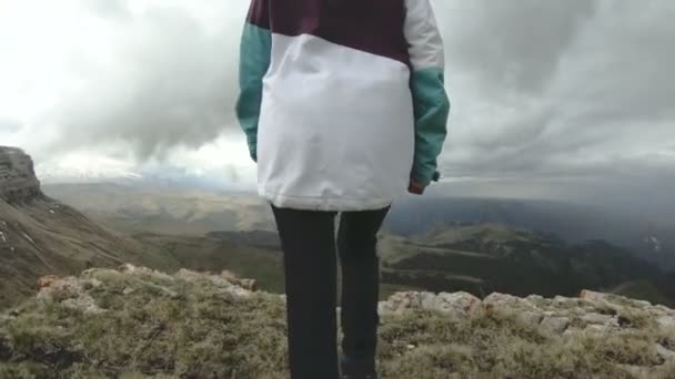 La niña camina en la naturaleza en una meseta junto a un alto acantilado. Concepto de viaje — Vídeos de Stock