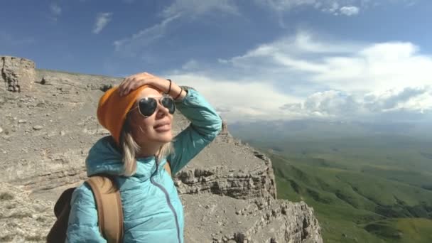 バックパックを持つ少女は、高い絶壁に近い高原の自然の中について説明します。旅行の概念 — ストック動画
