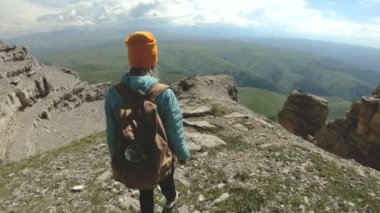 Bir kız bir sırt çantası ile doğada yüksek bir uçurumun yakınındaki bir plato üzerinde yürür. Seyahat kavramı
