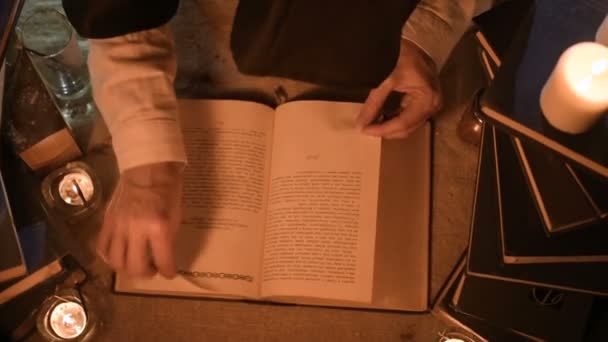 Großaufnahme Magierin in einem dunklen Raum mit Kerzenlicht auf der Suche nach einem Zauber in einem Buch. Low-Key Live-Kamera. Mystisch. kleine dof. Blick von oben — Stockvideo