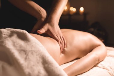 Yakın çekim erkek eller şifa yaparken bir koyu kozmetik ofiste genç bir kız için yağı ile masaj. Karanlık anahtar