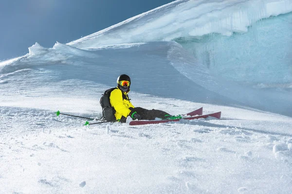 El esquiador atleta se sienta en una ladera nevada sobre el fondo de la pared de hielo. Esquí profesional. Vacaciones de invierno en las montañas —  Fotos de Stock