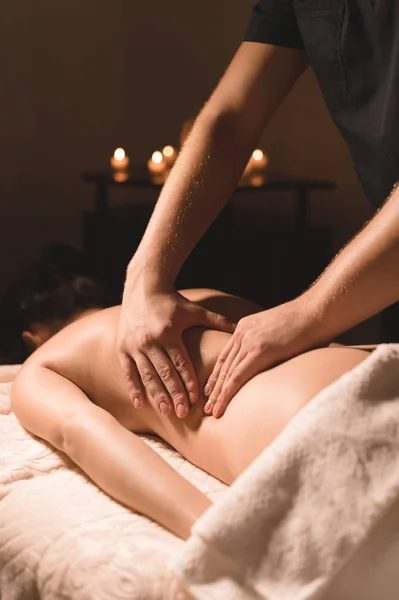 Close-up mannelijke handen doen helende massage met olie aan een jong meisje in een donkere cosmetologie kantoor. Donkere sleutel — Stockfoto