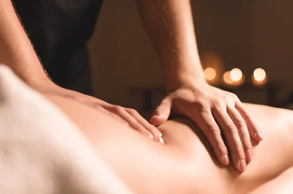Primeros planos manos masculinas haciendo masajes curativos con aceite a una joven en una oscura oficina de cosmetología. Llave oscura —  Fotos de Stock