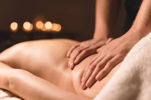 Close-up male hands doing healing massage with oil to a young girl in a dark cosmetology office. Dark key — Stock Photo, Image