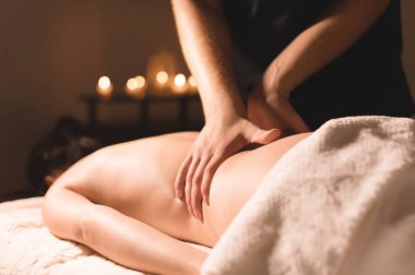 Yakın çekim erkek eller şifa yaparken bir koyu kozmetik ofiste genç bir kız için yağı ile masaj. Karanlık anahtar