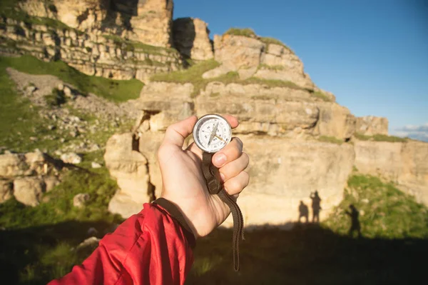 First-person view seeks direction with a compass in hand in the summer mountains. Search by destination. Three shadows of people on a rock. Silhouettes Company of three friends — Stock Photo, Image