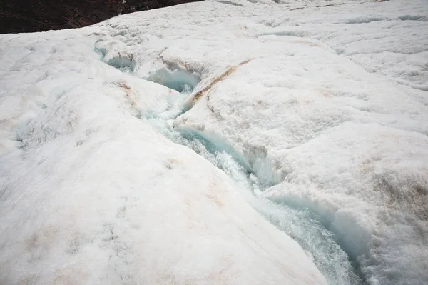 Um close-up de uma corrente de água de fusão flui ao longo de uma encosta através de uma fissura de geleira. Geleiras do Monte Elbrus. Norte do Cáucaso — Fotografia de Stock
