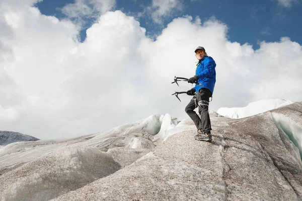 Cestovatel v čepici a brýle, stojící v zasněžených horách na ledovci. Cestovatel v přirozeném prostředí — Stock fotografie